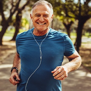 Senior man smiling while jogging outside