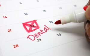 Red marker writing down dental appointment on calendar