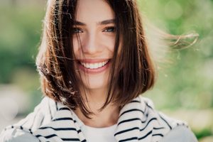 Woman with bobbed haircut outside smiling